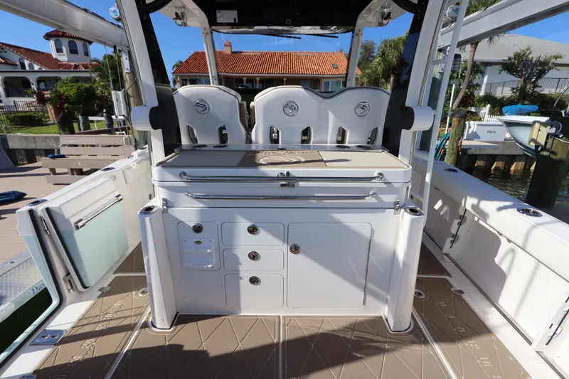 Slide: The Image of 2021 Edgewater 370CC boat interior with seating and storage, docked near waterfront homes. - 27