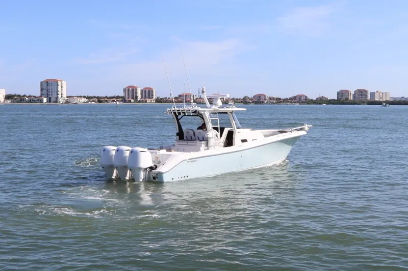 Slide: The Image of 2021 Edgewater 370CC boat cruising on a calm sea with city skyline in background. - 5