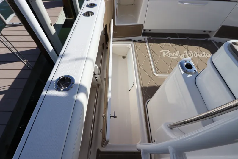 Slide: The Image of 2021 Edgewater 370CC boat interior with open storage compartment and rod holders. - 19