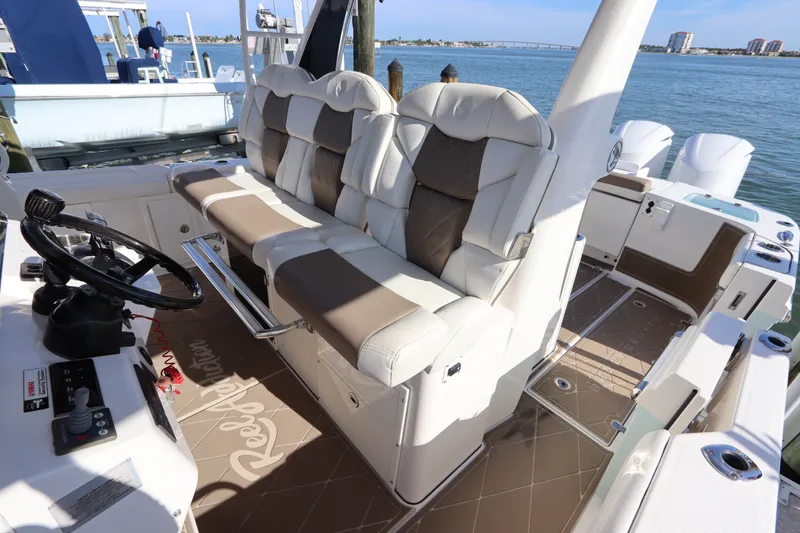 Slide: The Image of 2021 Edgewater 370CC boat interior with luxurious seating and steering wheel, docked by the water. - 31