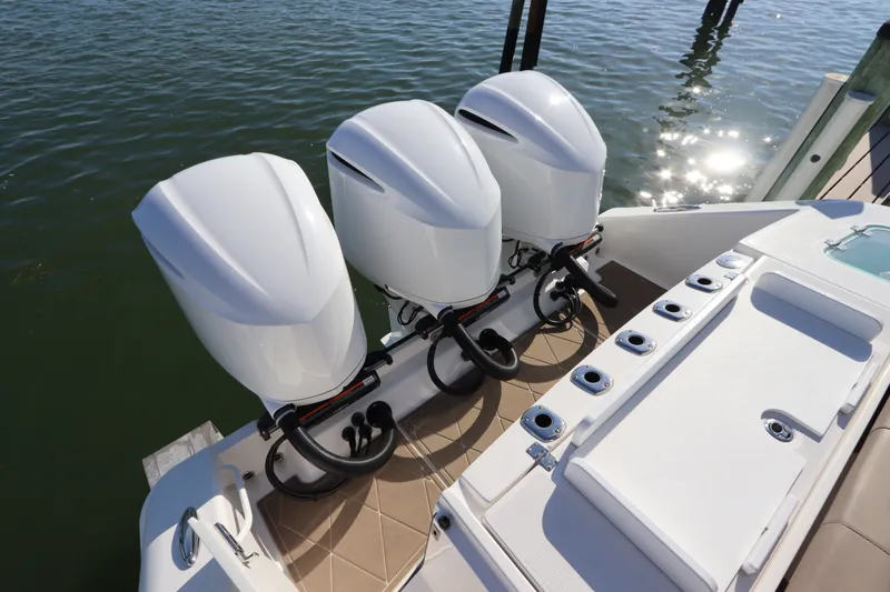 Slide: The Image of Triple outboard engines on a 2021 Edgewater 370CC boat, docked on calm water. - 11