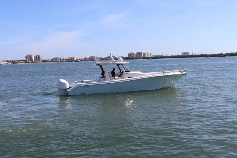 Slide: The Image of 2021 Edgewater 370CC boat cruising on a calm waterway with cityscape in the background. - 1