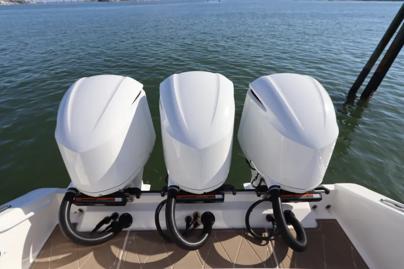 Slide: The Image of Triple outboard engines on a 2021 Edgewater 370CC boat, docked on calm water. - 12