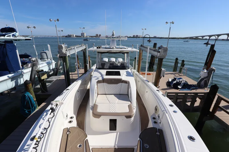 Slide: The Image of 2021 Edgewater 370CC boat docked at marina with scenic waterfront view. - 48