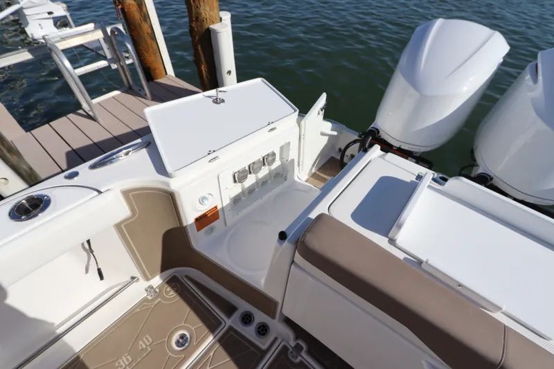 Slide: The Image of 2021 Edgewater 370CC boat with open storage compartment and twin outboard motors at dock. - 7