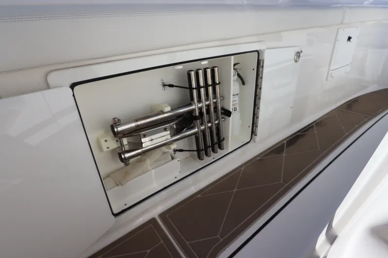 Slide: The Image of Storage compartment on a 2021 Edgewater 370CC boat, featuring stainless steel rod holders. - 23