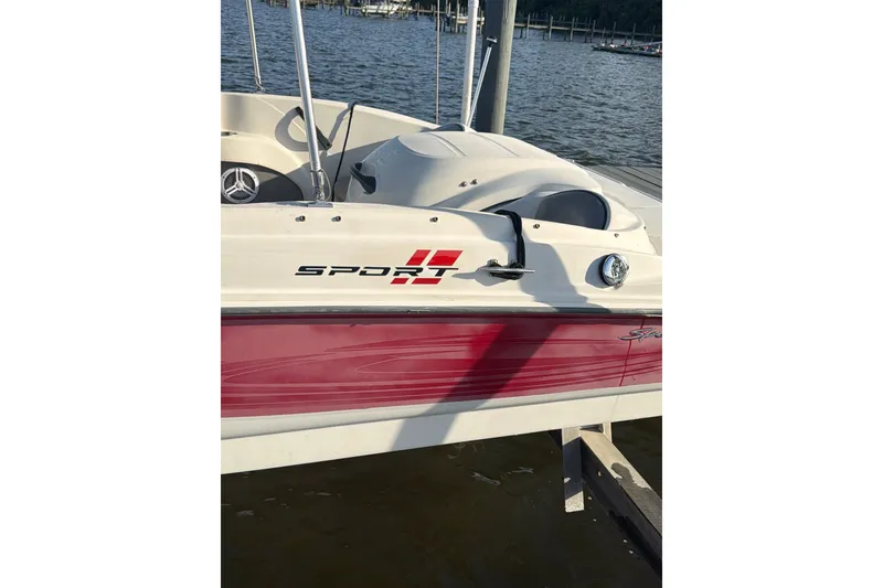 Slide: The Image of 2004 Sea Ray 180 Sport boat docked by the water, featuring red and white design. - 1