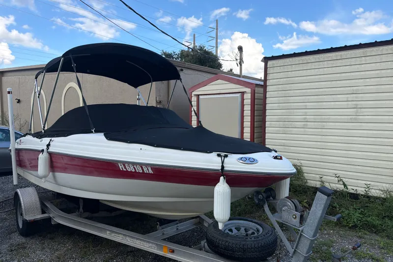 Slide: The Image of 2004 Sea Ray 180 Sport boat on trailer, covered and parked beside a shed. - 4