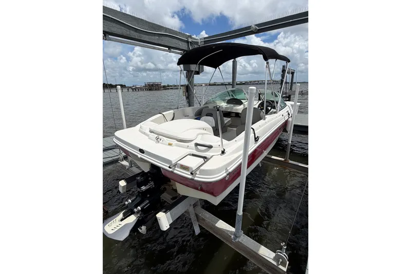 Slide: The Image of 2004 Sea Ray 180 Sport boat on lift, featuring a sleek design and canopy. - 2