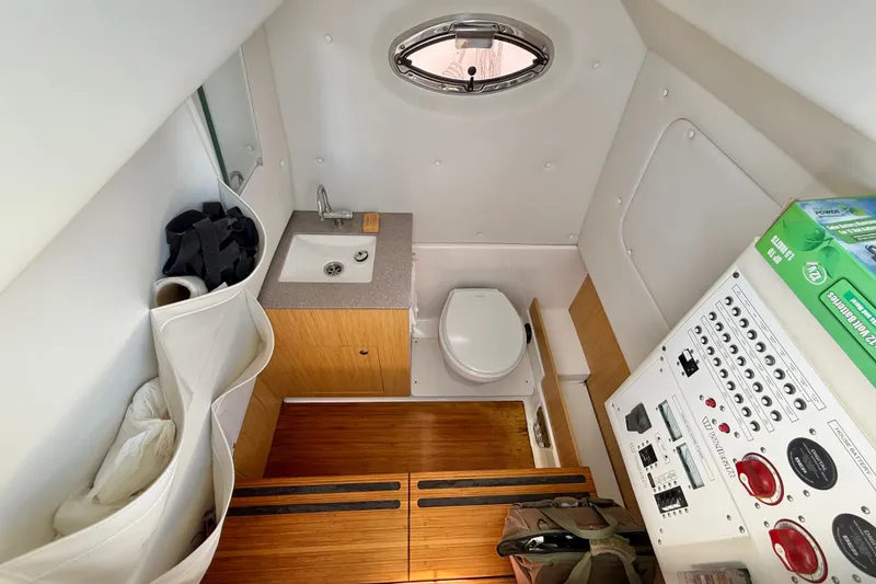 Slide: The Image of Interior of 2018 Wellcraft 302 Fisherman boat featuring a compact bathroom with sink and toilet. - 24