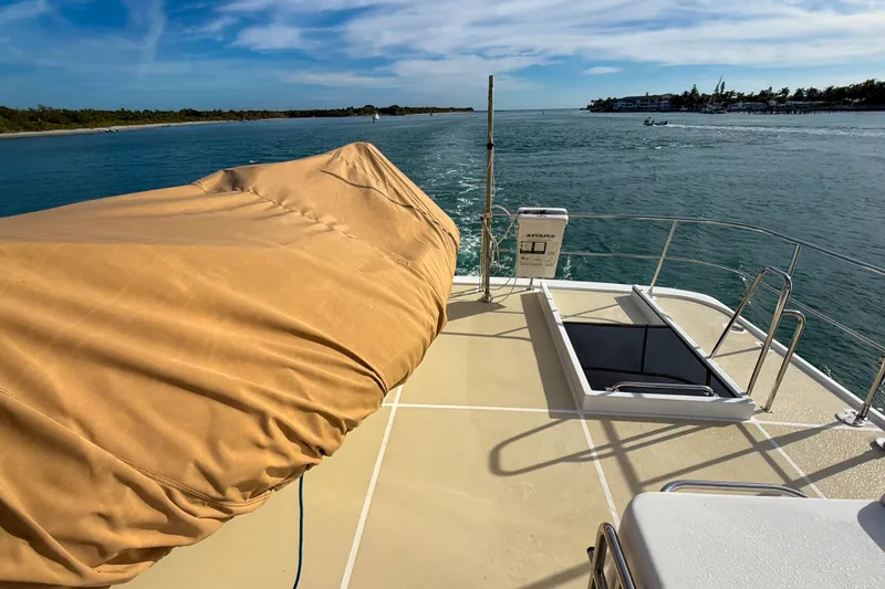 Slide: The Image of 2003 Grand Banks 64 Aleutian RP yacht deck with covered equipment, cruising on a sunny day. - 34