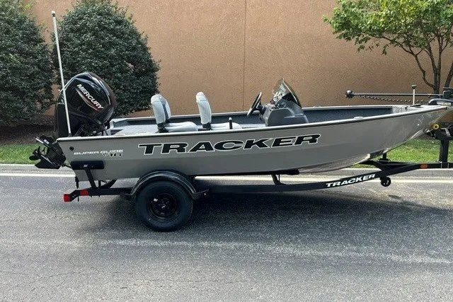 The Image of 2027 Tracker Super Guide V-16 SC boat on trailer, parked outdoors. - 0