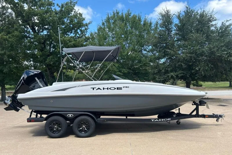 The Image of 2027 Tahoe 2150 boat on trailer, parked outdoors with trees in background. - 0