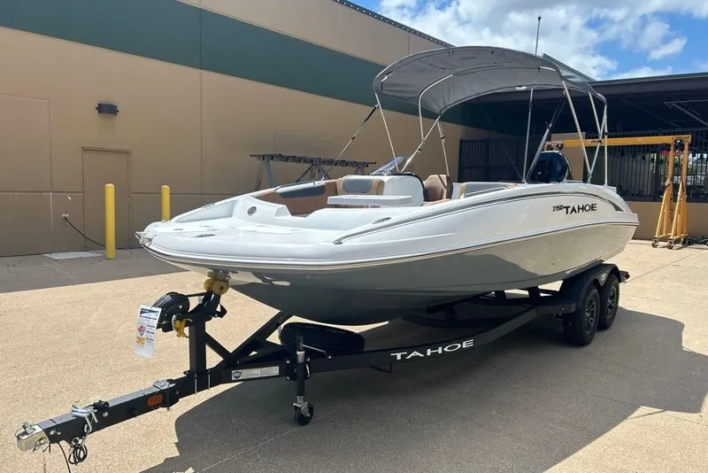 Slide: The Image of 2027 Tahoe 2150 boat on trailer, parked outdoors under a clear sky. - 12