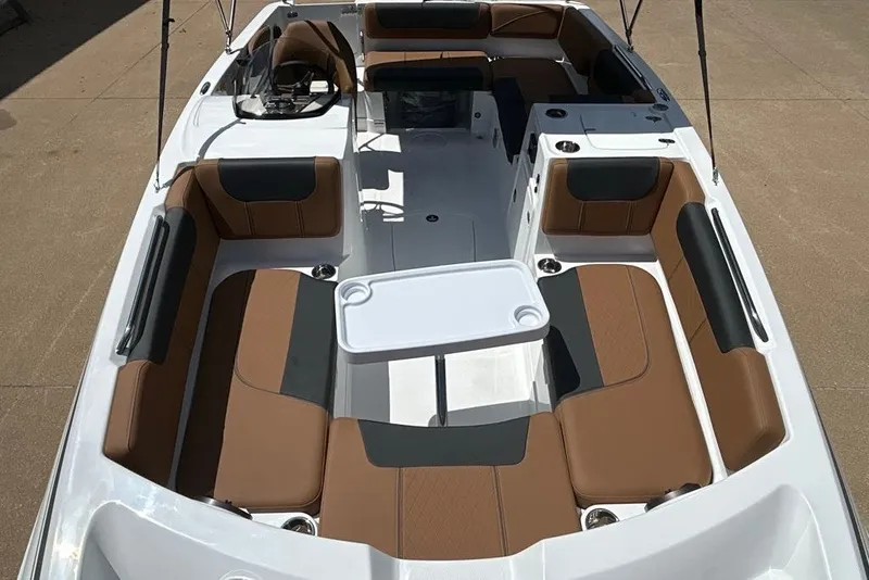 Slide: The Image of 2027 Tahoe 2150 boat interior with brown and black seating, white table, and steering console. - 10