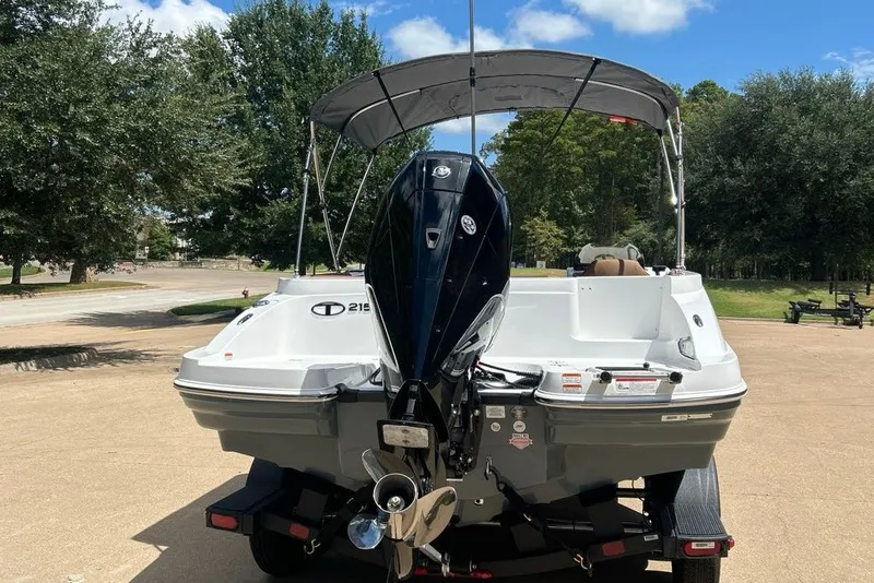 Slide: The Image of 2027 Tahoe 2150 boat with outboard motor on a trailer, parked outdoors. - 15