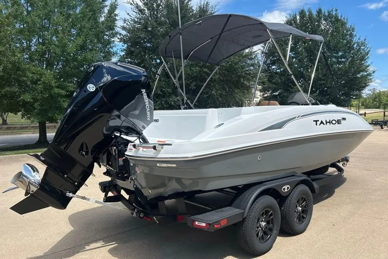 Slide: The Image of 2027 Tahoe 2150 boat on trailer with Mercury outboard motor, parked outdoors. - 1
