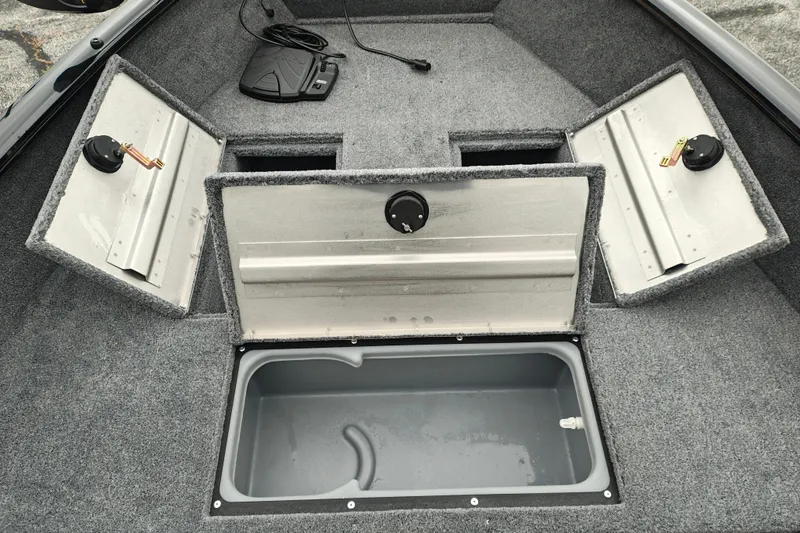 Slide: The Image of 2027 Tracker Super Guide V-16 T boat interior with open storage compartments and foot pedal. - 20