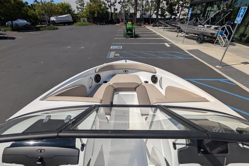 Slide: The Image of 2027 Tahoe 210 S boat with beige seating, parked in a lot near a showroom. - 6