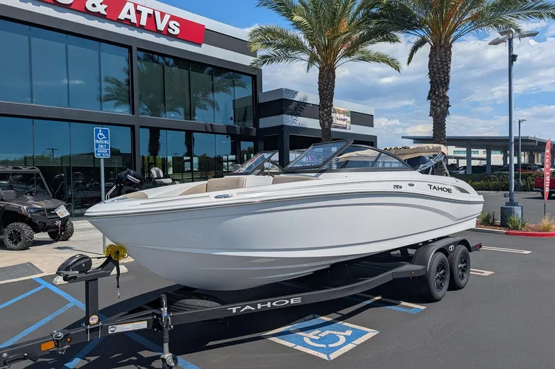 Slide: The Image of 2027 Tahoe 210 S boat on trailer outside dealership with palm trees. - 1