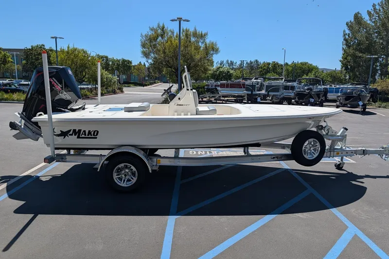 Slide: The Image of 2026 Mako 18 Pro Skiff boat on trailer in parking lot, sunny day. - 2