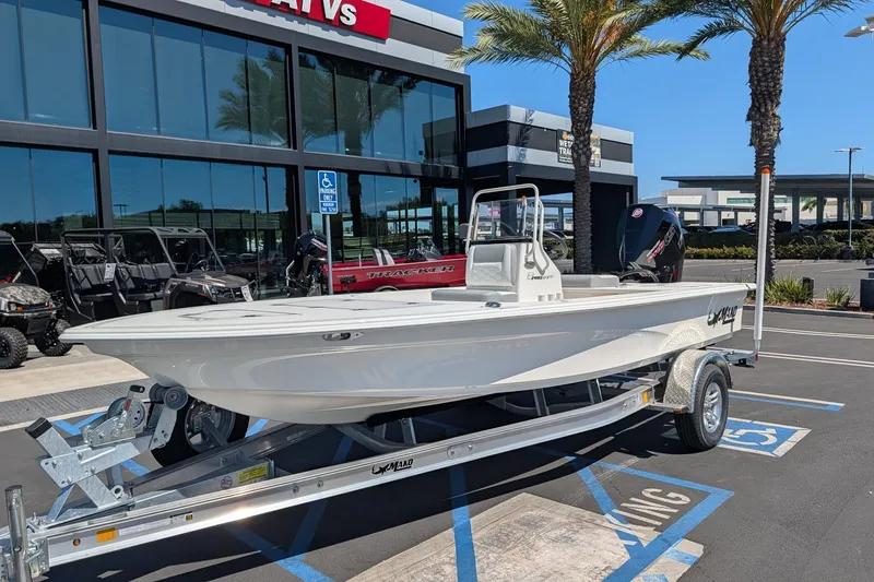 Slide: The Image of 2026 Mako 18 Pro Skiff boat on trailer, parked outside dealership with palm trees. - 3