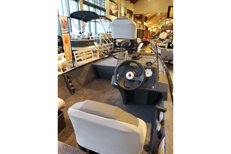 Slide: The Image of 2027 Tracker Bass Tracker Classic XL boat interior with steering wheel and seating in showroom. - 16
