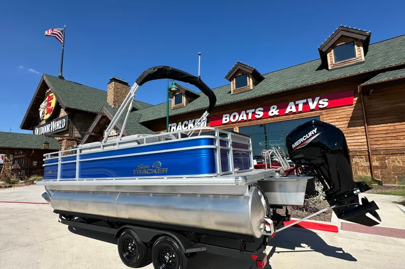 The Image of 2027 Sun Tracker SportFish 20 DLX pontoon boat outside a dealership with Mercury engine. - 1