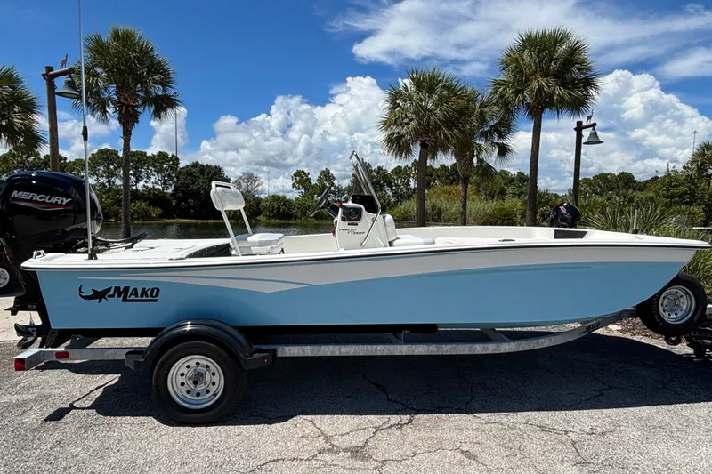 Slide: The Image of 2027 Mako Pro Skiff 17 CC boat on trailer, parked near palm trees under blue sky. - 1