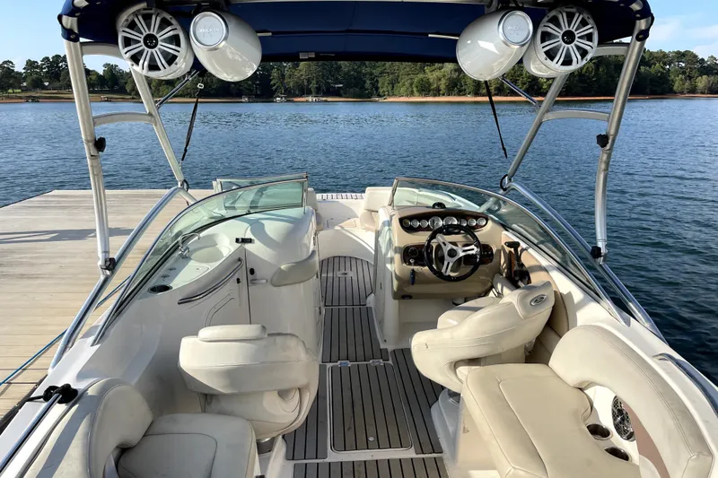 Slide: The Image of 2004 Chaparral Sunesta 236 boat interior with steering wheel and seating, docked by a lake. - 13