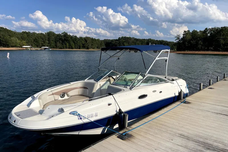 The Image of 2004 Chaparral Sunesta 236 boat docked on a serene lake under a blue sky. - 0