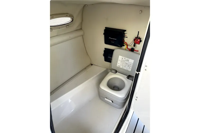 Slide: The Image of 2004 Chaparral Sunesta 236 boat interior with portable toilet and storage compartments. - 16
