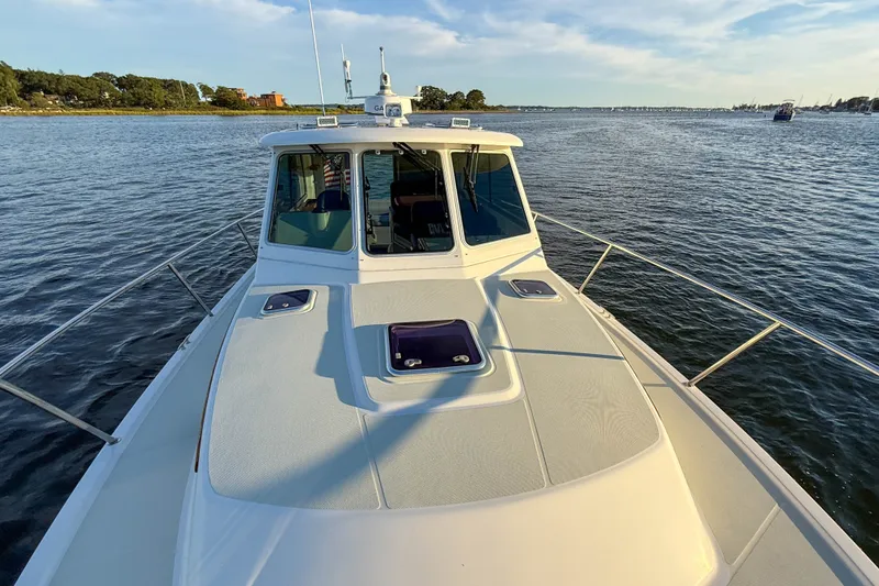 Slide: The Image of 2016 Back Cove 34 boat cruising on a calm river under a clear sky. - 38