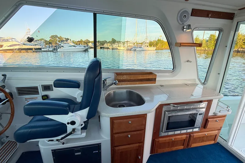 Slide: The Image of Interior of 2016 Back Cove 34 boat with helm, sink, and oven, overlooking marina. - 17