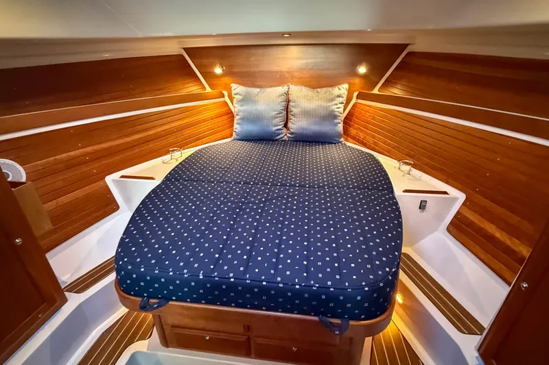 Slide: The Image of Cozy cabin interior of 2016 Back Cove 34 with wooden paneling and blue bedding. - 27