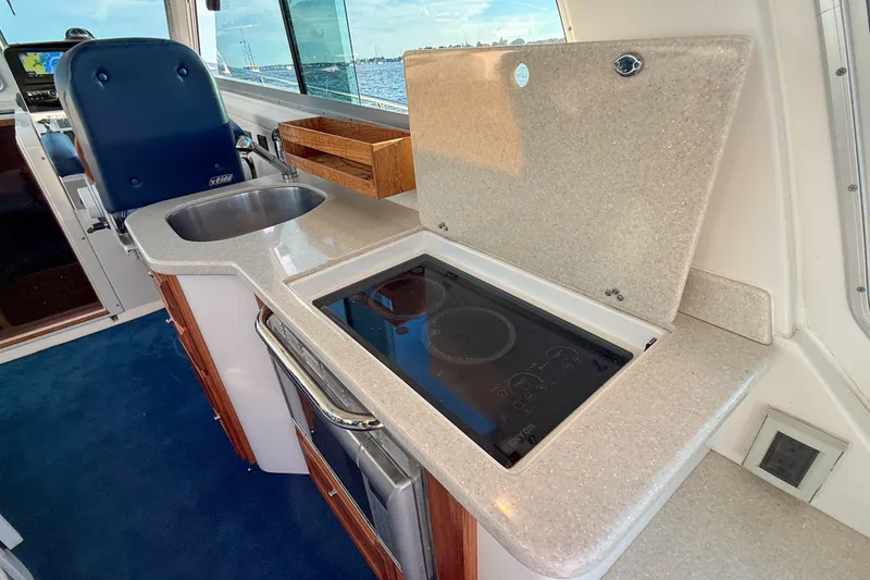 Slide: The Image of 2016 Back Cove 34 yacht interior with kitchenette, featuring sink and stovetop. - 16
