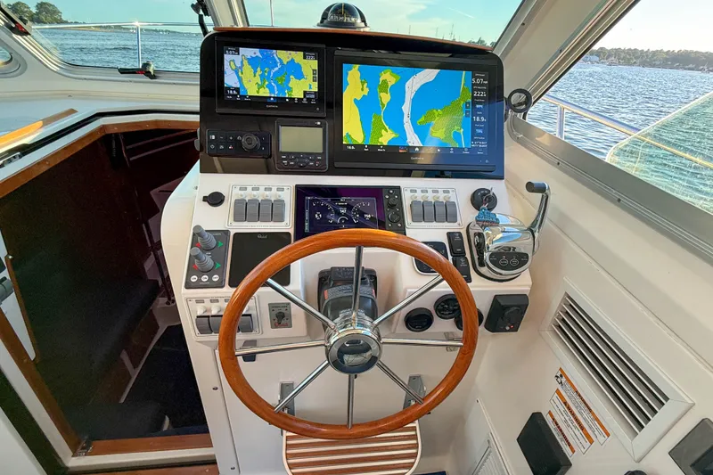 Slide: The Image of Helm of 2016 Back Cove 34 boat with navigation screens and wooden steering wheel. - 22