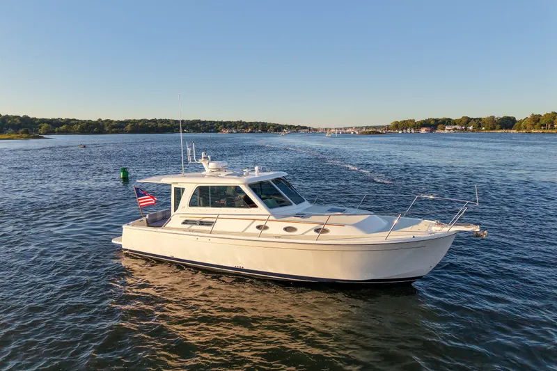 The Image of 2016 Back Cove 34 boat cruising on a serene lake under clear skies. - 0