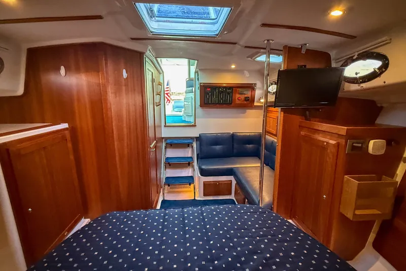 Slide: The Image of 2016 Back Cove 34 yacht interior with wood paneling, blue seating, and a mounted TV. - 30