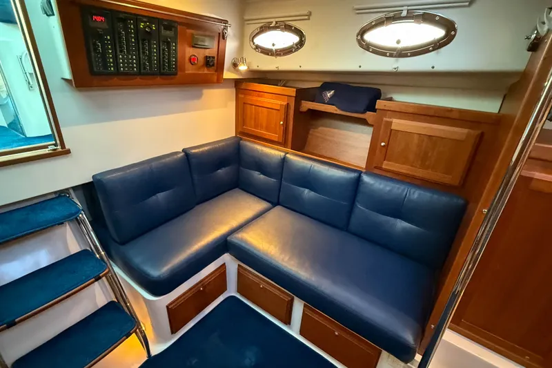 Slide: The Image of 2016 Back Cove 34 interior with blue leather seating and wooden cabinetry. - 26