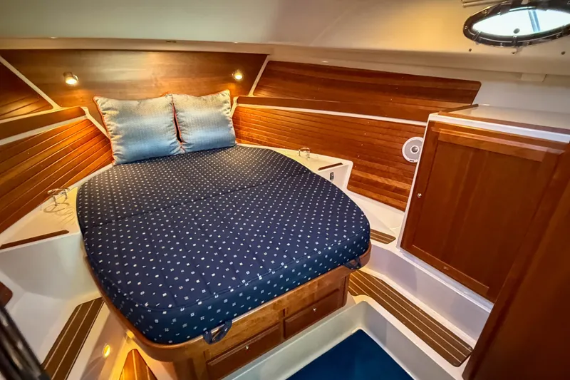 Slide: The Image of Cozy cabin interior of 2016 Back Cove 34 boat with wooden accents and blue bedding. - 28