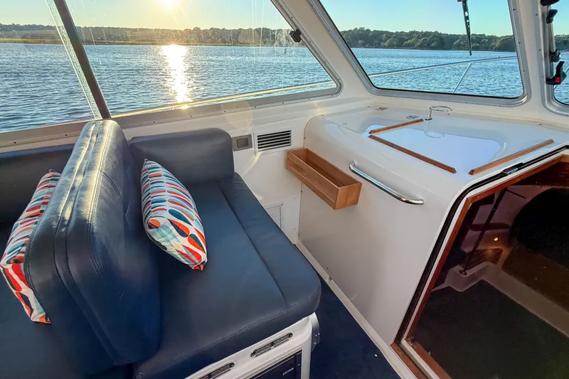 Slide: The Image of Interior of 2016 Back Cove 34 boat with blue seating and colorful pillows, overlooking water. - 13