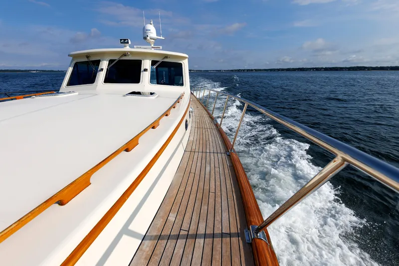 Slide: The Image of 2010 Vicem 64 yacht cruising on open water, showcasing sleek design and wooden deck. - 24
