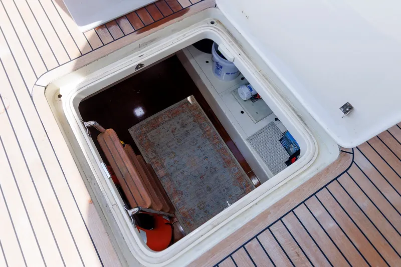 Slide: The Image of Open hatch on 2010 Vicem 64 yacht deck, revealing storage area with rug and equipment. - 89