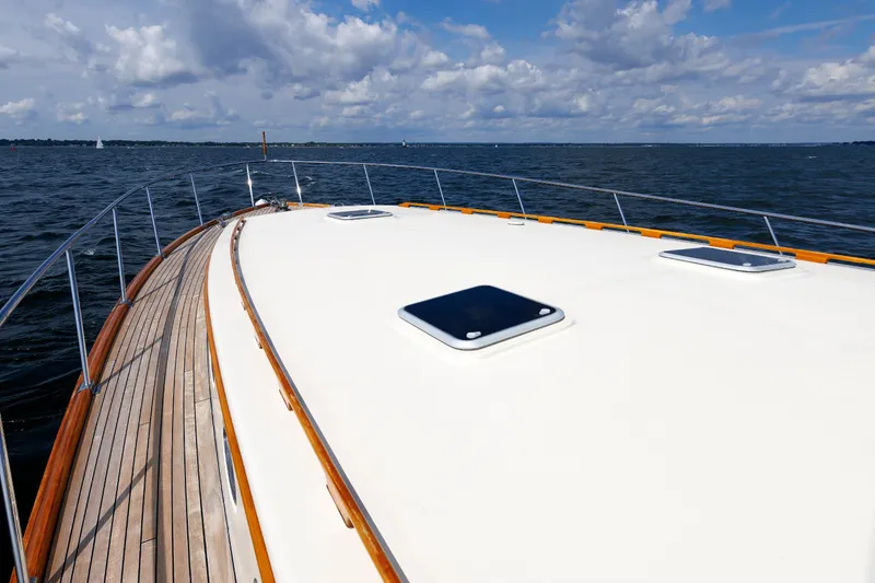 Slide: The Image of 2010 Vicem 64 yacht deck with wooden trim, sailing on open water under a cloudy sky. - 26
