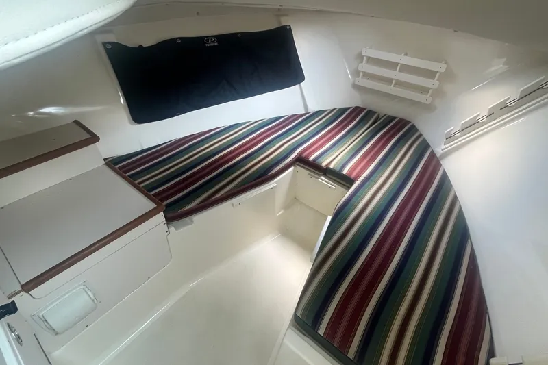 Slide: The Image of Interior cabin of 2004 Pursuit 2670 Denali LS with striped cushions and storage. - 13