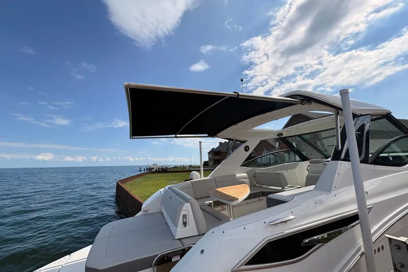 Slide: The Image of 2025 Sea Ray Sundancer 320 yacht docked by the water under a clear blue sky. - 35