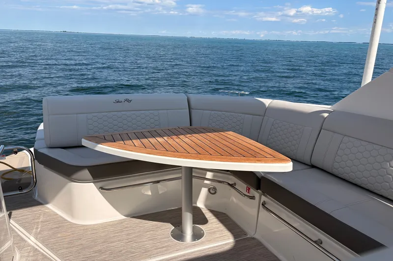 Slide: The Image of 2025 Sea Ray Sundancer 320 yacht interior with elegant seating and wooden table, ocean view. - 12