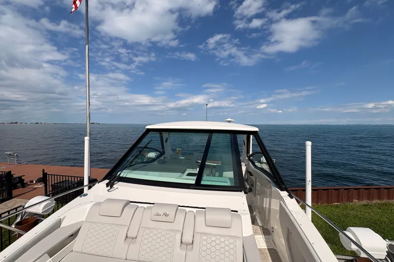 Slide: The Image of 2025 Sea Ray Sundancer 320 yacht docked by the ocean under a clear blue sky. - 24