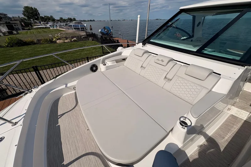 Slide: The Image of 2025 Sea Ray Sundancer 320 boat with spacious deck seating by the waterfront. - 23